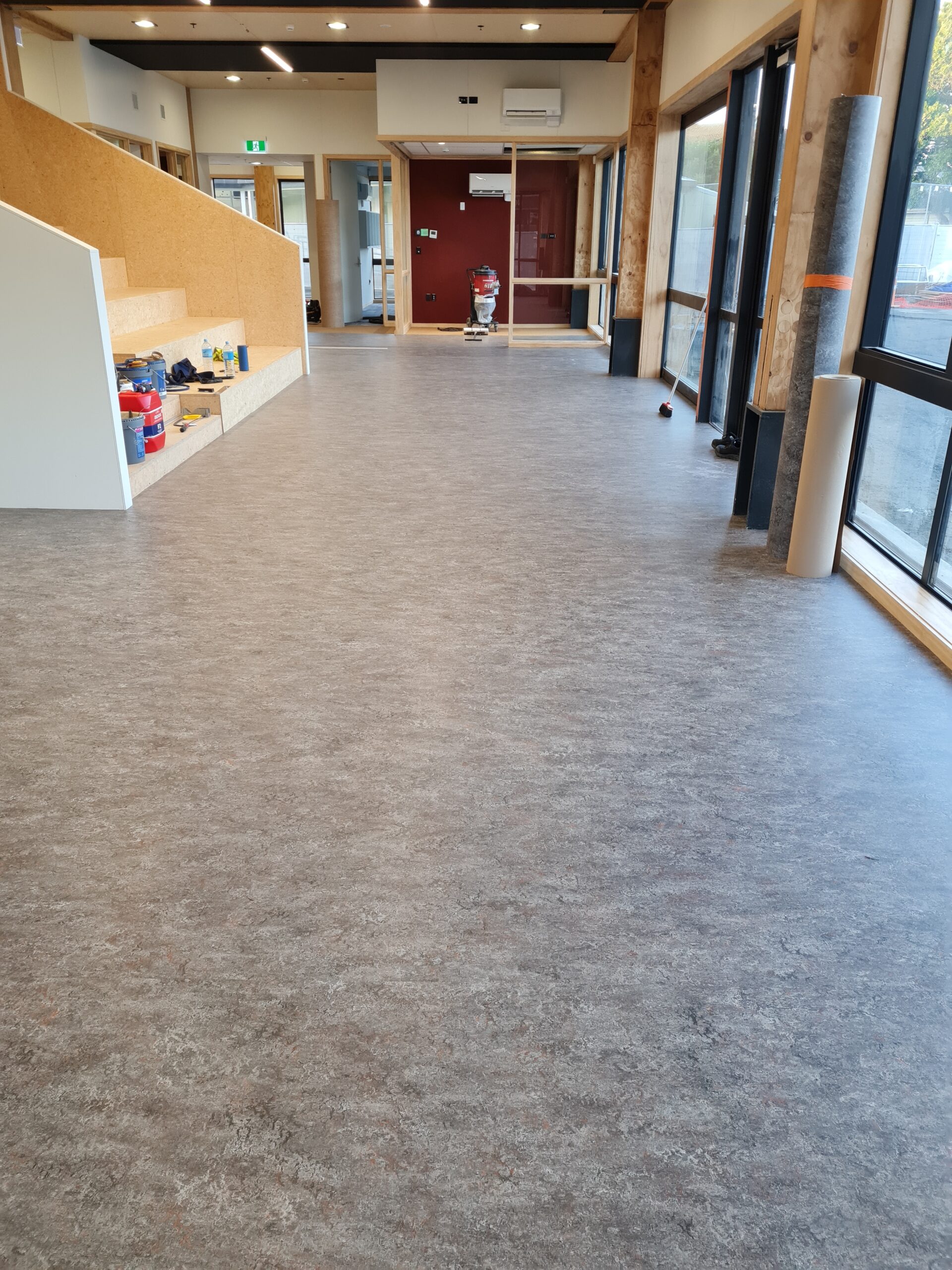 An airy entrance hall way with stairs to the left and grey vinyl flooring
