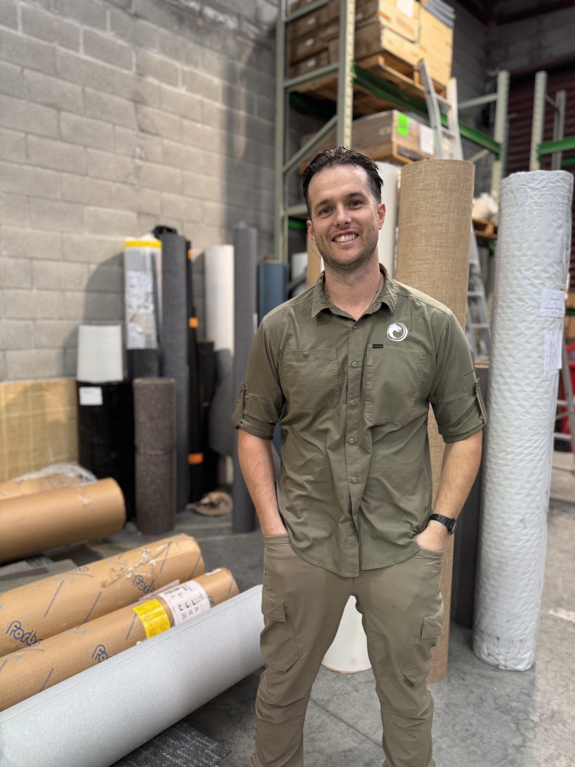 Director of Tinakori flooring standing with rolls of flooring behind him